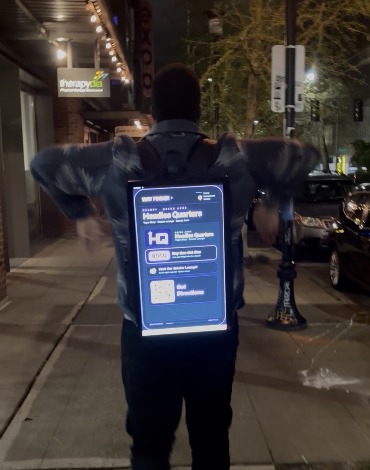 Ambassador wearing a lit Wayfinder LED backpack at night on a Queen Anne sidewalk