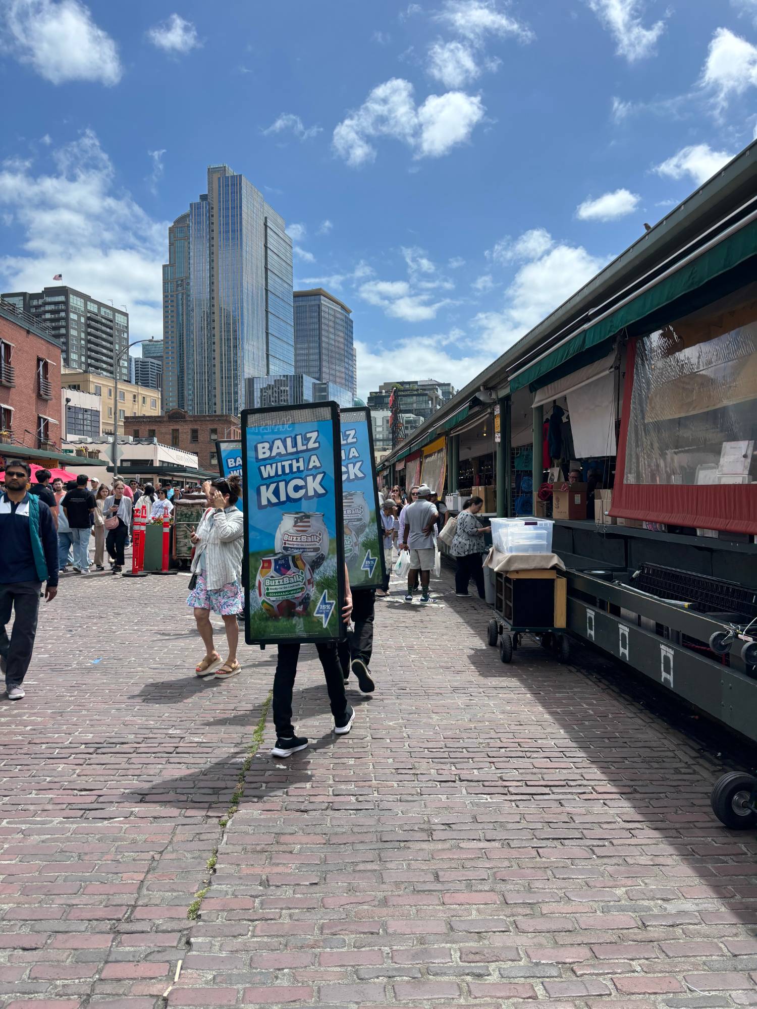 LED backpack ad walking through Pike Place Market crowds in daylight